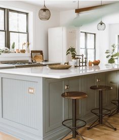 a kitchen with two stools in front of an island