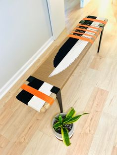 a plant is sitting in a pot on the floor next to a table made out of cardboard strips