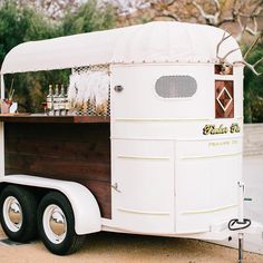 an old fashioned food truck is parked on the side of the road in front of some trees