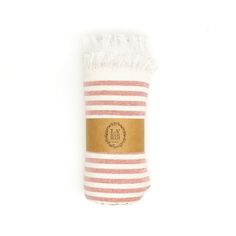 a pink and white striped towel with a brown label on the bottom that says fa