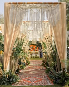 an outdoor wedding ceremony with white drapes and greenery on the aisle, surrounded by tropical plants