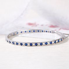 Add sophisticated style to her look with this exquisite bangle bracelet. Crafted in sterling silver, this darling design showcases blue round cut stones alternating with shimmering white round stones. Dazzling stones are always an excellent choice and she'll absolutely adore this delightful bracelet.Weight: 13.32 gWidth: 3.8 mmHeight: 2.6 mmThickness: 3.8 mmMaterial: 925 SilverStone Type: Jeulia® StonePlating Color: SilverBracelet Size: 180 mm Classic Round Sapphire Diamond Bracelet, Sapphire Diamond Tennis Bracelet With Round Shape, Sapphire Tennis Bracelet With Round Diamonds, Sapphire Diamond Tennis Bracelet With Round Cut, Channel Set Round Bangle For Anniversary, Round Channel Set Bangle For Anniversary, Classic Sapphire Tennis Bracelet With Round Shape, Sapphire Cubic Zirconia Bracelets, Elegant White Gold Bangle With Channel Set