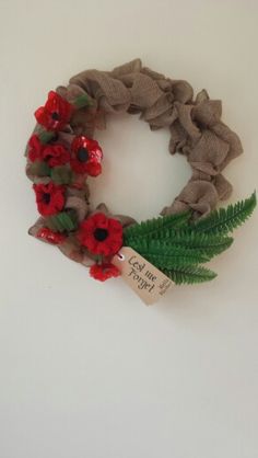 a wreath made out of burlock with red flowers and green leaves on it