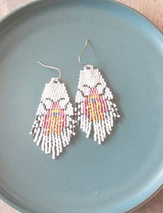 two small beaded earrings on a blue plate