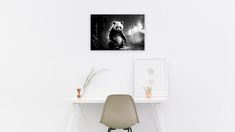 a black and white photo of a bear sitting on a desk next to a chair