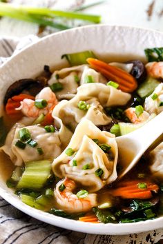 a white bowl filled with dumplings and vegetables