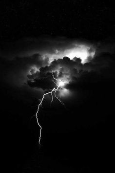 a black and white photo of lightning in the night sky with dark clouds over water