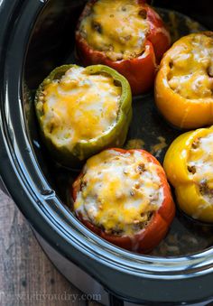 four stuffed peppers in the slow cooker ready to be cooked with cheese on top