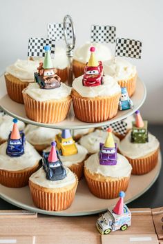 cupcakes with cars and race flags are on a cake platter, ready to be eaten