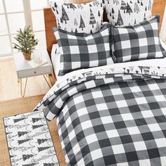 a bed with black and white plaid comforter set on top of it next to a potted plant