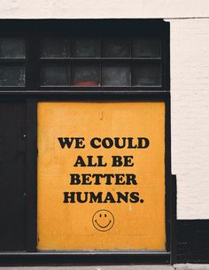 a yellow sign that says we could all be better humans on the side of a building