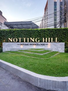 a sign that says notting hill in front of some buildings and grass on the ground