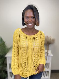 a smiling woman wearing a yellow sweater and jeans