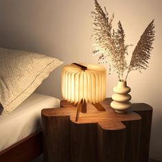 a wooden table topped with two vases filled with flowers next to a night stand