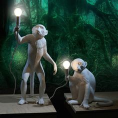 two statues of monkeys holding lamps in their hands