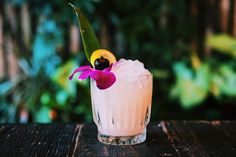 a pink cocktail with a flower on the rim