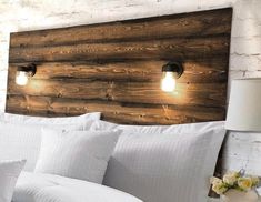 a bed with white pillows and two lights on the headboard