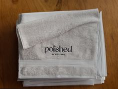 stack of folded white towels on top of a wooden table with the word polished printed on it