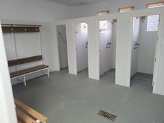 an empty bathroom with white stalls and benches in it's stall area, next to a bench