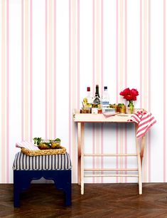 a small table with food and drinks on it next to a striped wallpapered room