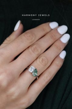 a woman's hand wearing a ring with an oval shaped green and white diamond