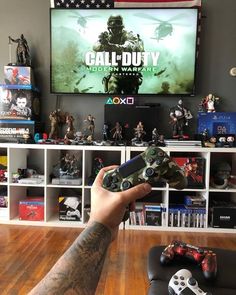 a person holding a controller in front of a television with the call of duty on it