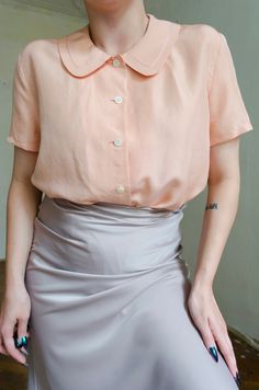 Truly romantic peachy pink silk blouse. Features the cutest Peter Pan collar, button up style and short sleeves. Detailed specs & measurements below: Fabrics: 100% silk Tag size:  1 Brand: Portdimare Best fits: XS - S Condition: superb, no flaws to note MEASUREMENTS *taken seam to seam. not doubled, taken flat Shoulders: 41 cm |  16.1" Bust: 52 cm | 20.4" Sleeve length: 19 cm | 7.4" Length: 67 cm | 26.3" For reference, our model is size S and is 5"2 tall  SHIPPING Sent as Latvian Standard Post. Chic Short Sleeve Peach Blouse, Feminine Pink Collared Top, Elegant Short Sleeve Pink Blouse, Elegant Pink Short Sleeve Blouse, Vintage Pink Blouse With Peter Pan Collar, Pink Short Sleeve Feminine Blouse, Classic Pink Summer Blouse, Pink Silk Blouse, Pastel Blouse