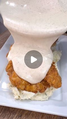 a fried chicken sandwich is covered in gravy on top of mashed potatoes