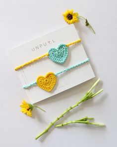 two crocheted heart bracelets on top of a card next to sunflowers