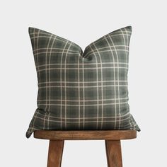 a green plaid pillow sitting on top of a wooden stool