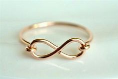 a gold ring with an infinite knot on it's side, sitting on top of a white surface