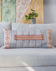 a white couch with a blue and red pillow on top of it next to a potted plant