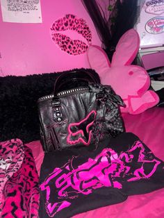 pink and black items are sitting on a bed