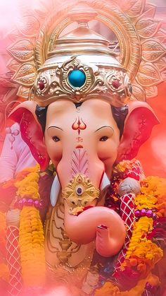 an elephant statue is adorned with gold and jewels on it's head, in front of a pink background