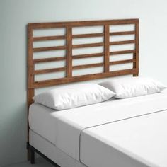 a bed with white pillows and wooden headboard