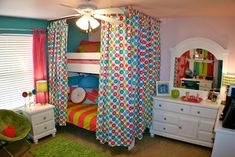 a child's bedroom decorated in bright colors and polka dot bedding with curtains