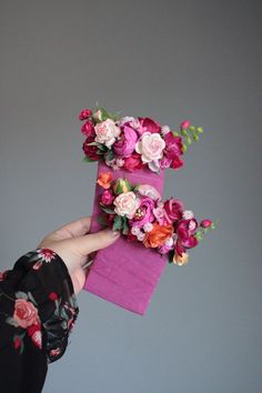 a person holding two small pink boxes with flowers on them, one is purple and the other is red