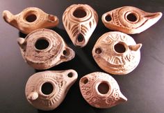 six clay vases sitting on top of a black table next to eachother