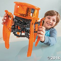 a young boy holding up an orange plastic model