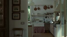 an open kitchen with pots and pans hanging from the ceiling, next to a dining room table