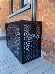 a black metal box sitting on top of a wooden floor next to a brick building