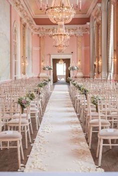 the aisle is lined with white chairs and floral centerpieces for an elegant wedding ceremony