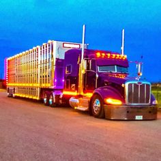 a large semi truck is parked on the side of the road at night with its lights on