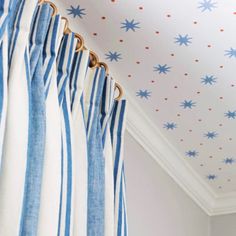 blue and white curtains hanging on the side of a curtain rod in front of a ceiling with stars painted on it