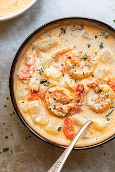 a close up of a bowl of soup with shrimp and grits in it on a white surface