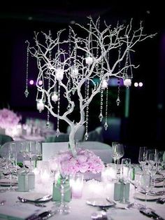 a table topped with lots of white and pink flowers next to tall centerpieces