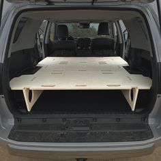 the back end of a van with an open hatchback and wooden table on it