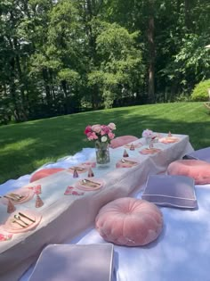 a table set up with pink and white plates, napkins and cake on it