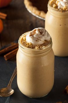 two mason jars with whipped cream and pumpkin pie toppings in them on a table