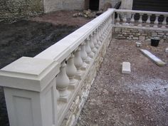 a white fence sitting on top of a dirt field next to a stone wall and building